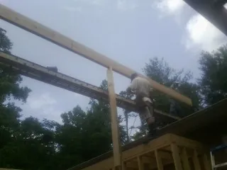 Carpenter setting a ridge beam over a new addition frame — Ice Dam Removal by Roofing Brothers in Astoria