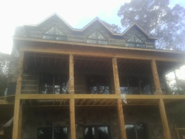 Dormers and porch framing on a large log home under construction — Roof Coating work by our crew in Astoria