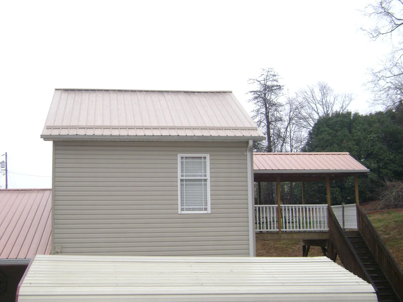 Tan metal roofs on a two story addition and attached porch, from a Roof Replacement job in Astoria